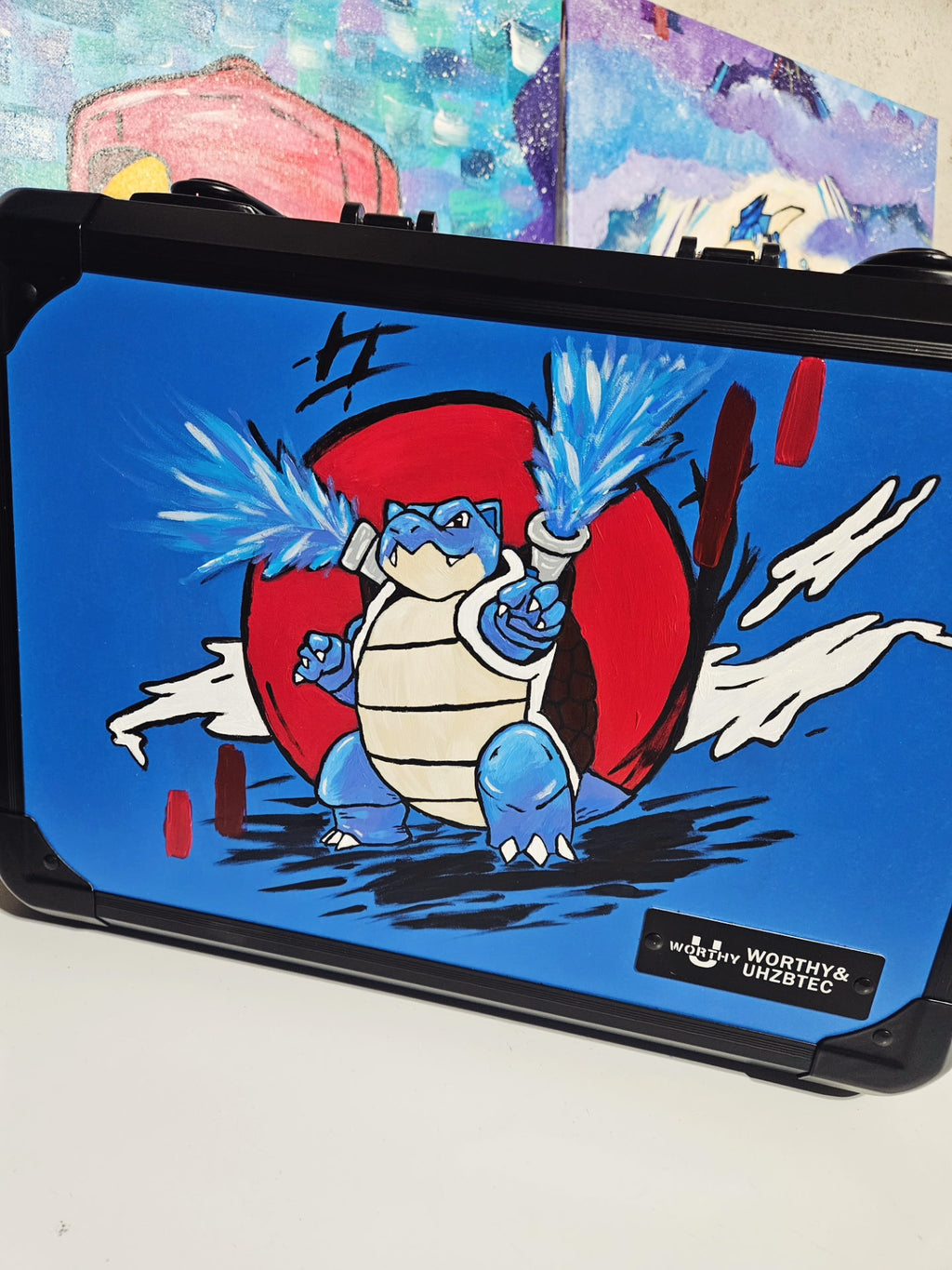 Angled front view of custom hand-painted Blastoise 3-row slab case — blue case with Blastoise firing twin water cannons against a bold red circle background, freehand acrylic artwork by 5/14 Apparel