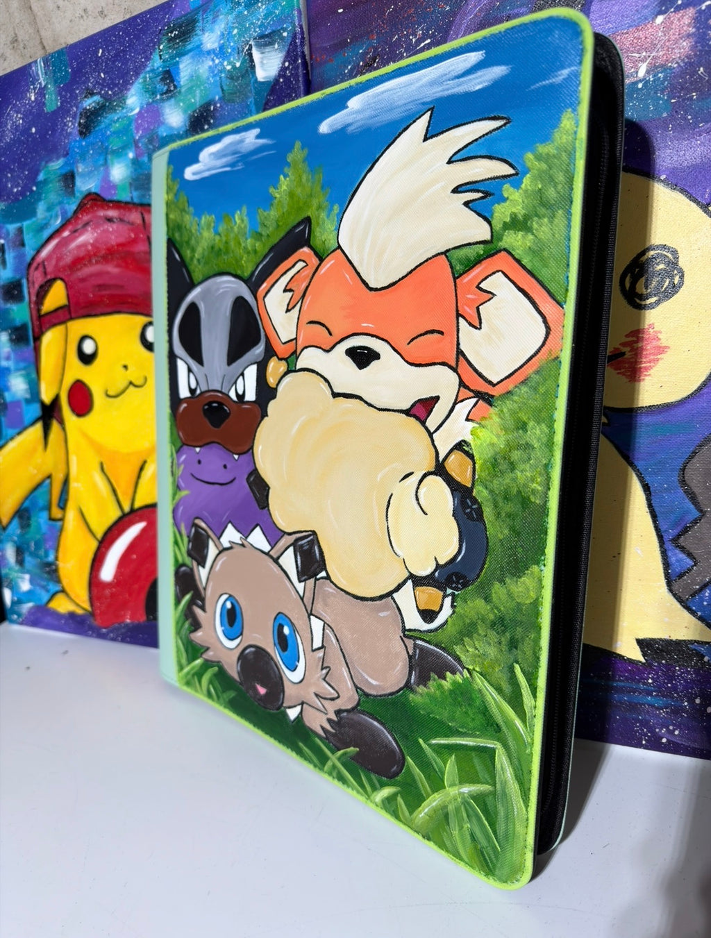 Side view of 5/14 Apparel Custom Rockruff Houndour and Growlithe hand-painted binder — Rockruff, Houndour, and Growlithe with Ditto/Mareep Toy meadow scene on lime green Ultrapro binder displayed at convention, one-of-one hand-painted Pokemon card binder
