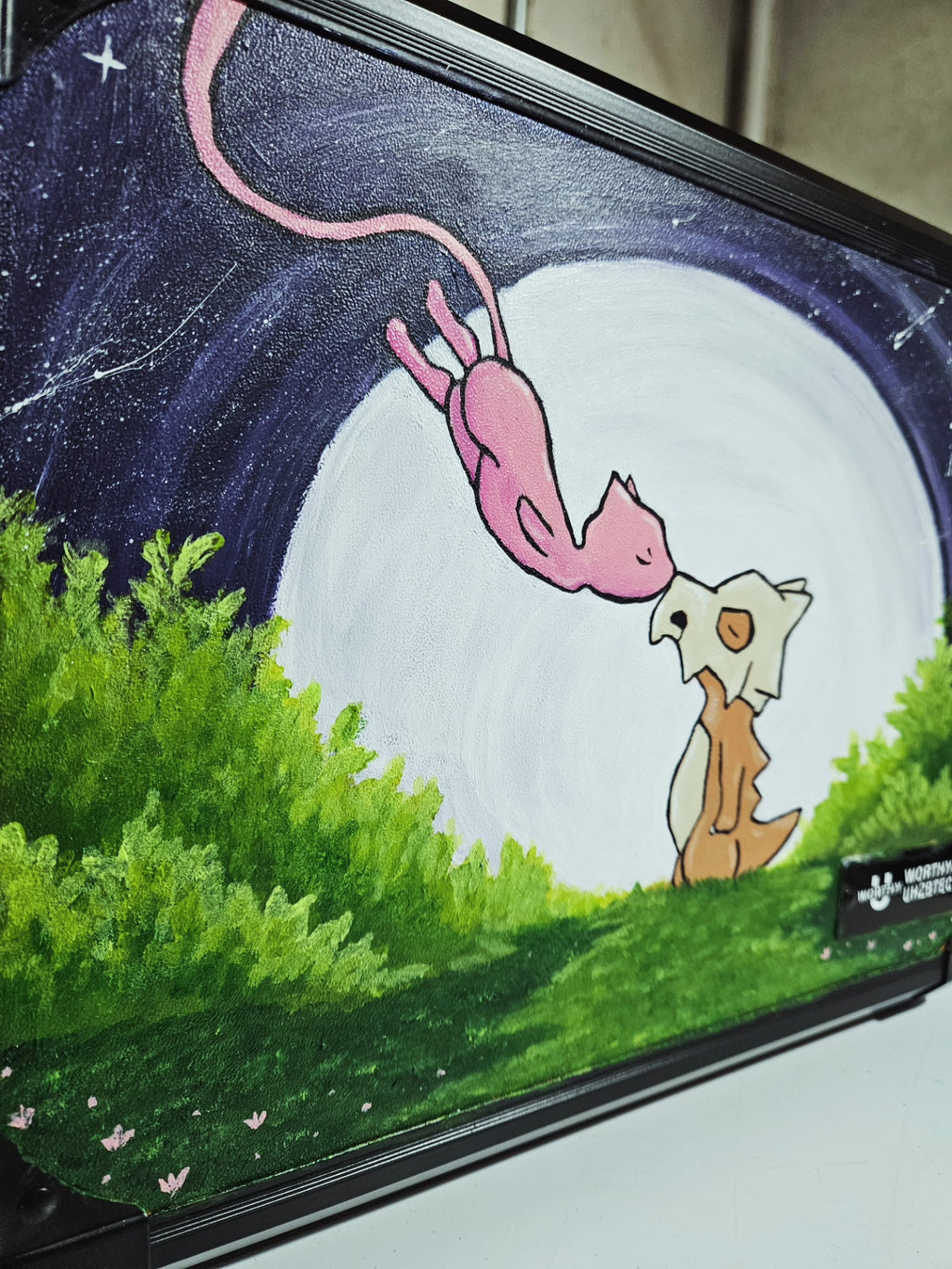 Close-up of hand-painted Cubone and Mew artwork on custom orange 3-row slab case — moonlit night scene with green foliage, acrylic on slab case by 5/14 Apparel
