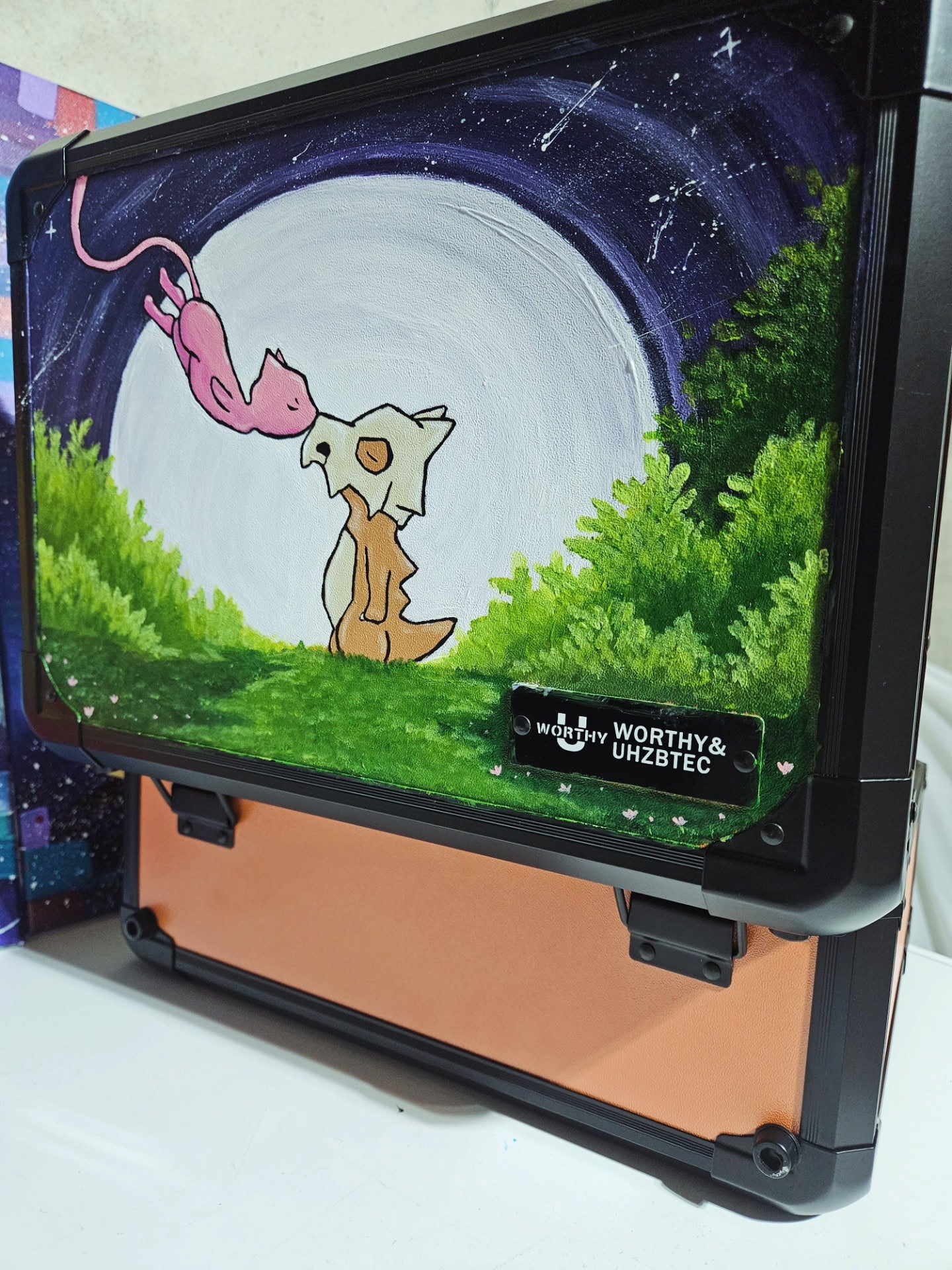 Side angle of custom hand-painted Cubone and Mew Pokemon slab case in orange — one-of-a-kind acrylic artwork sealed with UV and scratch-resistant coating by 5/14 Apparel
