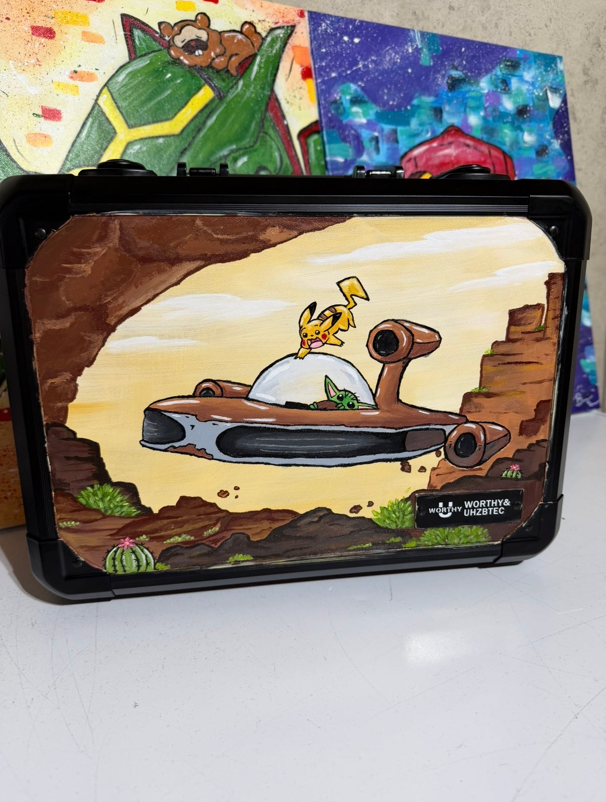 5/14 Apparel x Worthy & Uhzbtec — hand-painted Pikachu riding the Razor Crest with Grogu in the cockpit, desert canyon scene, black 3-row key lock slab case


