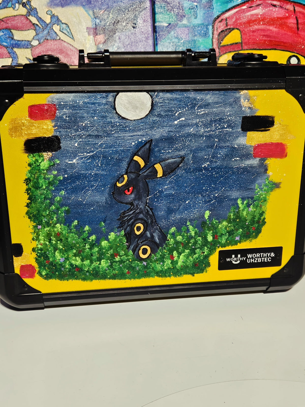 Front view of custom hand-painted Umbreon 3-row slab case — dark Umbreon with glowing red eyes and yellow ring markings in a moonlit forest clearing on yellow background, freehand acrylic artwork by 5/14 Apparel