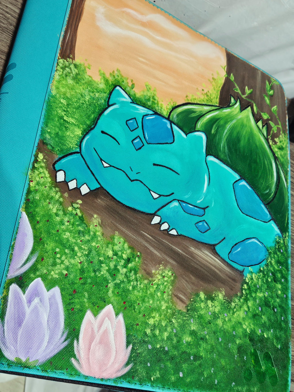 Angled view of custom hand-painted Bulbasaur Pokemon card binder — freehand acrylic artwork sealed with UV and scratch-resistant coating by 5/14 Apparel
