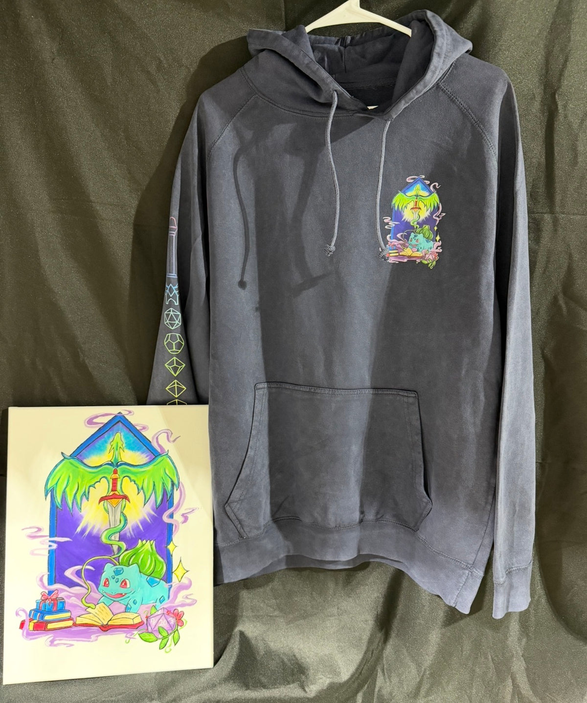 5/14 Apparel custom art and apparel package example — gray hoodie with hand-painted Bulbasaur wizard chest print and sleeve design paired with matching original acrylic canvas painting