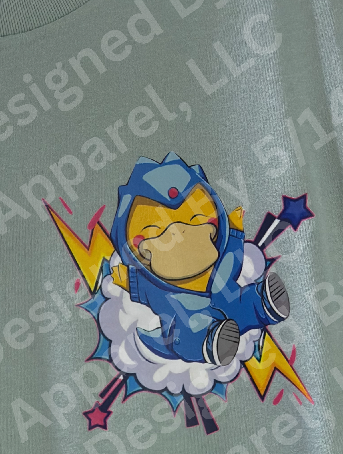 Close-up of Poncho Psyduck graphic on dusty blue tee — Psyduck in blue superhero poncho with yellow lightning bolts and stars design by 5/14 Apparel